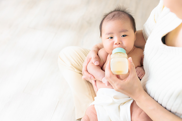 女性に抱きかかえられながらミルクを飲む赤ちゃん